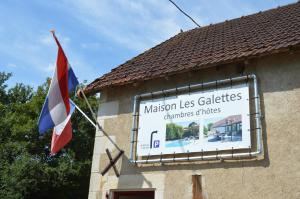 een bord aan de zijkant van een gebouw met een vlag bij Chambres d'hôtes Maison Les Galettes in Rezay