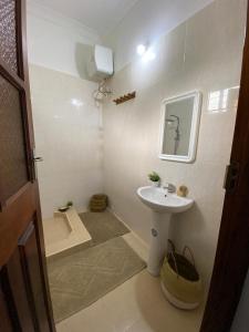 a small bathroom with a sink and a toilet at Pumzika Kendwa Villa in Kendwa