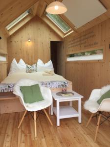 a bedroom with a bed and two chairs and a table at refugium am see in Seeboden
