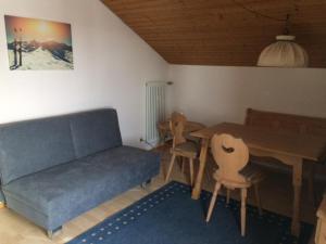 uma sala de estar com um sofá, uma mesa e cadeiras em Ferienwohnung Alpenveilchen im Oberallgäu em Missen-Wilhams