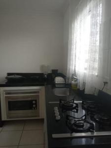 a kitchen with a stove and a microwave at Sua casa na praia em Cabo Frio in São Pedro da Aldeia