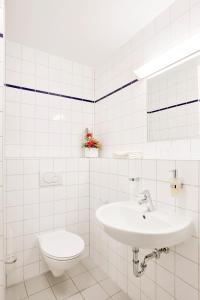 a white bathroom with a sink and a toilet at Gästehaus Pauline in Berlin