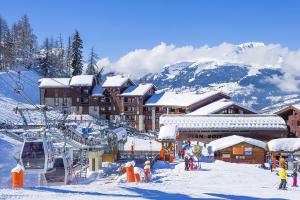 a ski lodge with snow covered mountains in the background at Appartement - La Plagne - Les Coches - 7 Personnes - Pieds des pistes in La Plagne Tarentaise