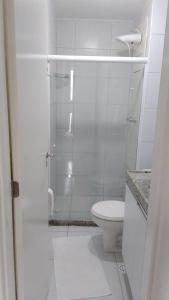 ein weißes Badezimmer mit Dusche und Toilette in der Unterkunft Muro Alto Condomínio Clube - Porto de Galinhas in Porto De Galinhas