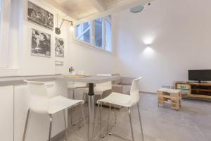 a kitchen with white chairs and a table and a tv at Loft-Relax in Bologna
