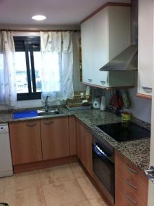 a kitchen with wooden cabinets and a stove top oven at Apartamento Aguamar in Denia