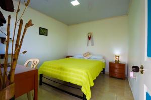 a bedroom with a bed with a yellow blanket on it at Casa Campesina Hostel in Armenia