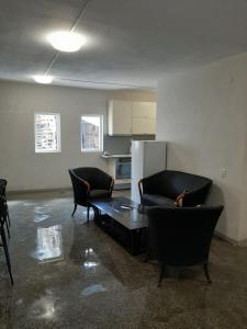 a living room with two chairs and a table and a refrigerator at Hostel Iliana Общежитие Илияна in Elin Pelin