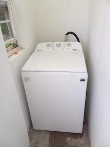 a small white refrigerator in a room with a window at Jamaica Vacation Montego Bay Guesthouse Cottage villa in Montego Bay