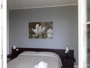 1 dormitorio con 1 cama con un cuadro de flores en la pared en Magnolia Room & Breakfast, en Faenza