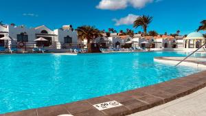 a pool at a resort with palm trees and white buildings at Casthotels Fuertesol Bungalows in Caleta De Fuste