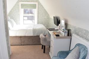 a bedroom with a bed and a desk with a computer at The Castleton in Swanage