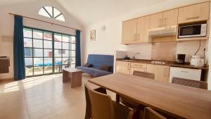 cocina y sala de estar con mesa y sofá en Casthotels Fuertesol Bungalows, en Caleta de Fuste