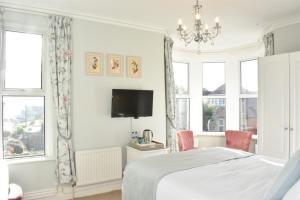 a bedroom with a bed and two chairs and a tv at The Castleton in Swanage