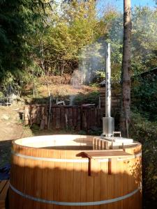 a wooden hot tub in a yard with a fountain at Cabana Farmec Ciubăr - Dézsabáj Kulcsosház in Sovata +8 photos