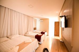 Cette chambre comprend deux lits et une télévision. dans l'établissement TRIUNFO PAPO HOTEL, à Triunfo