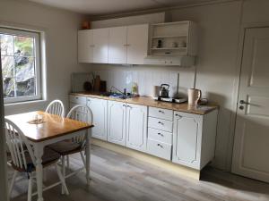 cocina con armarios blancos, mesa y ventana en Apartment for holiday in Nyksund, en Nyksund