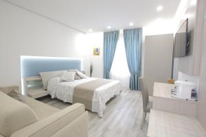 ein weißes Schlafzimmer mit einem Bett und einem Sofa in der Unterkunft B&B La Stazione in Diamante