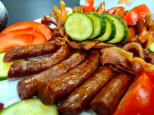 a plate of sausage and vegetables with cucumbers and tomatoes at Beconia Riverside in Văliug