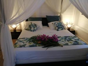 a white bed with a flower arrangement on it at Blue Kaz Caraïb in Pointe-Noire