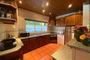 cocina con armarios de madera y suelo de baldosa naranja en Green Villa Gerês, en Valdosende