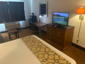 a hotel room with a television and a bed and a desk at Brentwood Inn & Suites in Hobbs