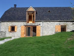 kamienny dom z drewnianymi drzwiami na zielonym wzgórzu w obiekcie Gîte Pause du Berger w mieście Saint-Pastous
