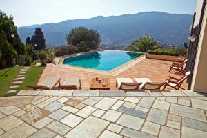 a swimming pool with chairs and a view of the mountains at Hortensia Villa - Infinity Pool & Sea Views by Explore Andros in Andros