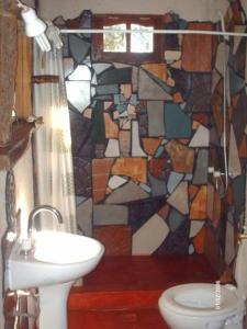 a bathroom with a sink and a stained glass shower curtain at Giramundo Hostel y Posada Eco-Cultural in San Marcos Sierras