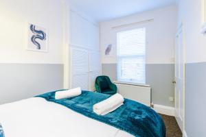 a white bedroom with a bed and a green chair at Smart home near Chester City Centre in Chester