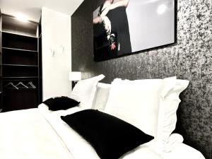 a white bed with black pillows in a bedroom at Luxury Suite Koksijde 212- Adult only in Koksijde