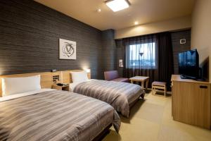 a hotel room with two beds and a flat screen tv at Hotel Route Inn Matsue in Matsue