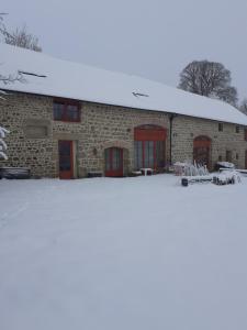 a brick building with red doors in the snow at Auverg'Nature Chambre Cocon in Espinasse