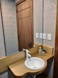 een badkamer met een witte wastafel en een spiegel bij Flores da Montanha 402A in Gramado