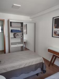 una camera con letto, scrivania e tavolo di Flores da Montanha 402A a Gramado