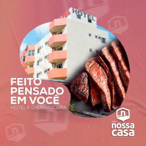 un cartel con algo de carne en un plato con un edificio en Hotel Nossa Casa, en Ijuí