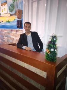 mężczyzna siedzący przy biurku z choinką świąteczną w obiekcie اللوكاندة الجديدة New Hotel w Aleksandrii