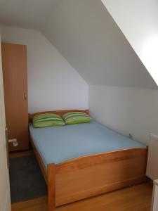 Una cama con almohadas verdes en una habitación pequeña. en Zlatiborsko jutro 1, en Zlatibor