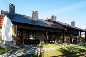 a stone house with a porch and a patio at Apartamentos Rurales Camín Real in La Caridad