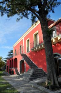 a red building with stairs next to a tree at Palazzo Rosso in Riposto