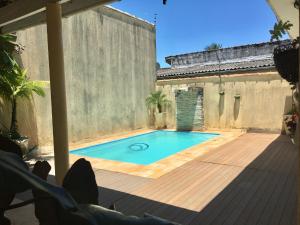 a swimming pool in a backyard with a wooden deck at Casa Itanhaém - Prainha in Itanhaém