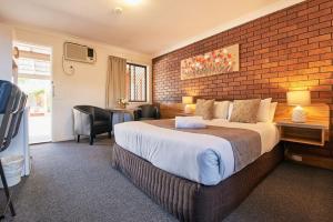 
a hotel room with a bed, chair, and nightstand at Ruthven Street Motor Inn in Toowoomba

