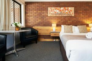 
a hotel room with a bed, chair and a lamp at Ruthven Street Motor Inn in Toowoomba
