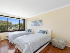 two beds in a room with a window at Watersedge in Currarong