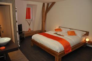 1 dormitorio con 1 cama con edredón naranja y blanco en Le Relais du Château Monney, en Cournillens