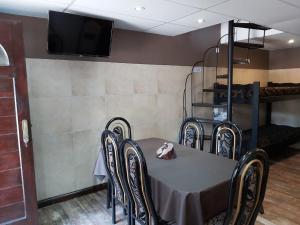 comedor con mesa, sillas y TV en Apartamentos Esquiu en Mar del Plata