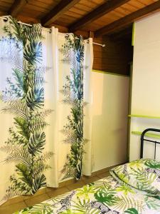 1 dormitorio con 1 cama y cortina con plantas en Studio avec jardin clos et wifi a Basse Terre, en Basse-Terre
