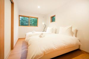 two beds in a room with two windows at Chalet Villars in Hakuba