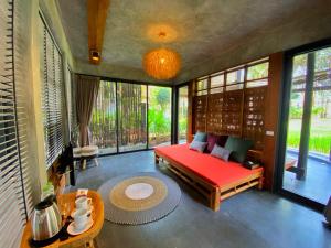 a room with a bed and a table and windows at LA A NATU Pranburi in Sam Roi Yot