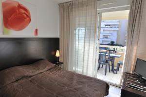 a bedroom with a bed and a balcony with a table at Residhotel Cannes Festival in Cannes